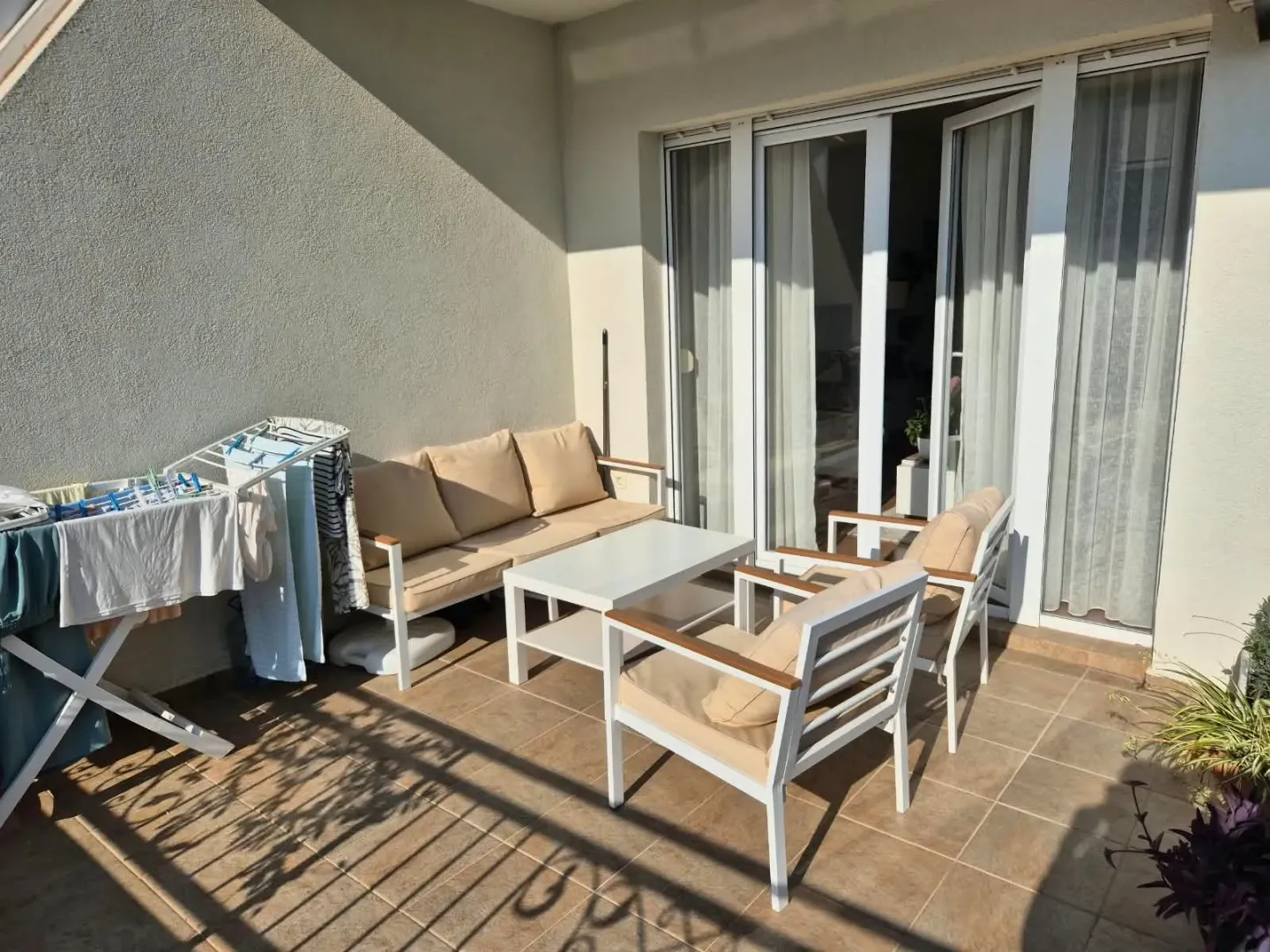 Terrace with seating furniture and a clothes drying rack.