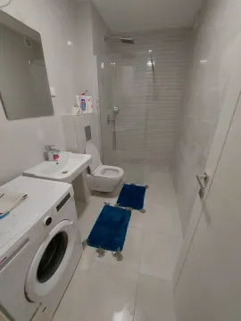 Modern bathroom with a shower cabin, toilet, and washing machine. - image 5