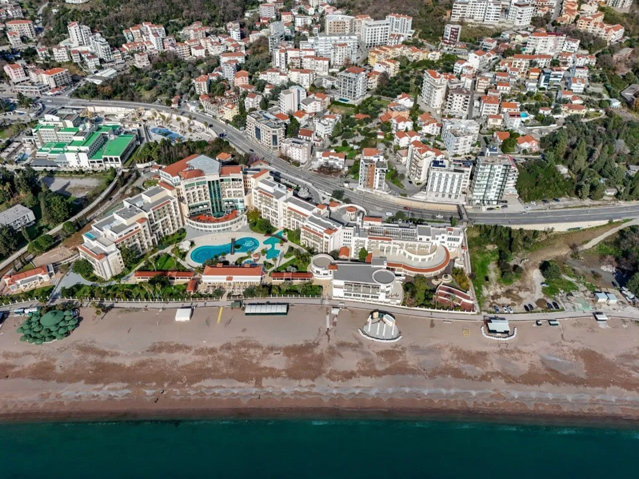 Pogled iz vazduha na hotelski kompleks uz obalu mora i gradsku zon.