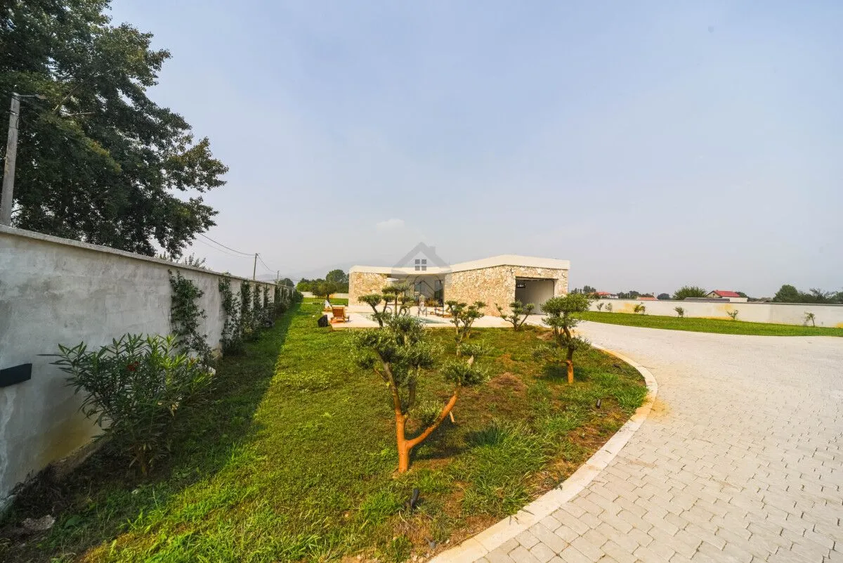 View of the courtyard and driveway with landscaped green areas and a fence.