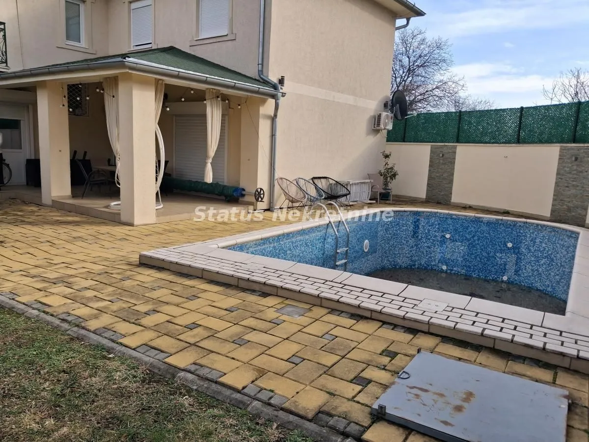 Pogled na dvorište sa bazenom i natkrivenom terasom ispred kuće.