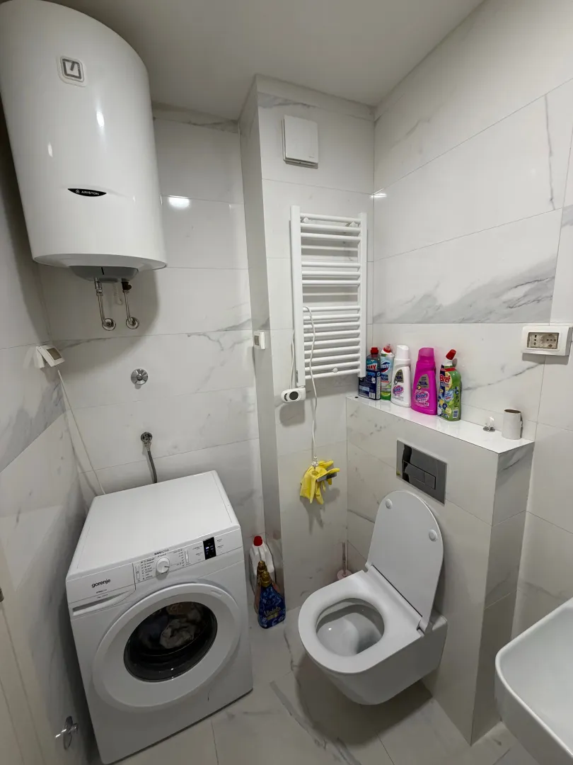 Modern bathroom with a toilet, washing machine, and water heater.