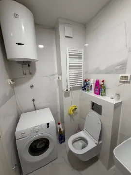 Modern bathroom with a toilet, washing machine, and water heater. - image 6