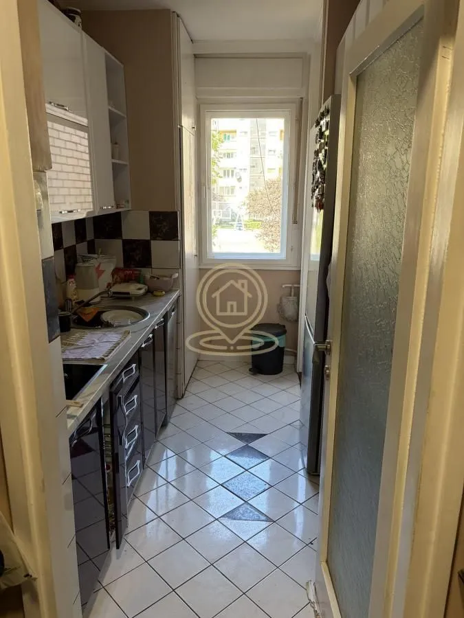 Small narrow kitchen with white cabinets and a window at the end.