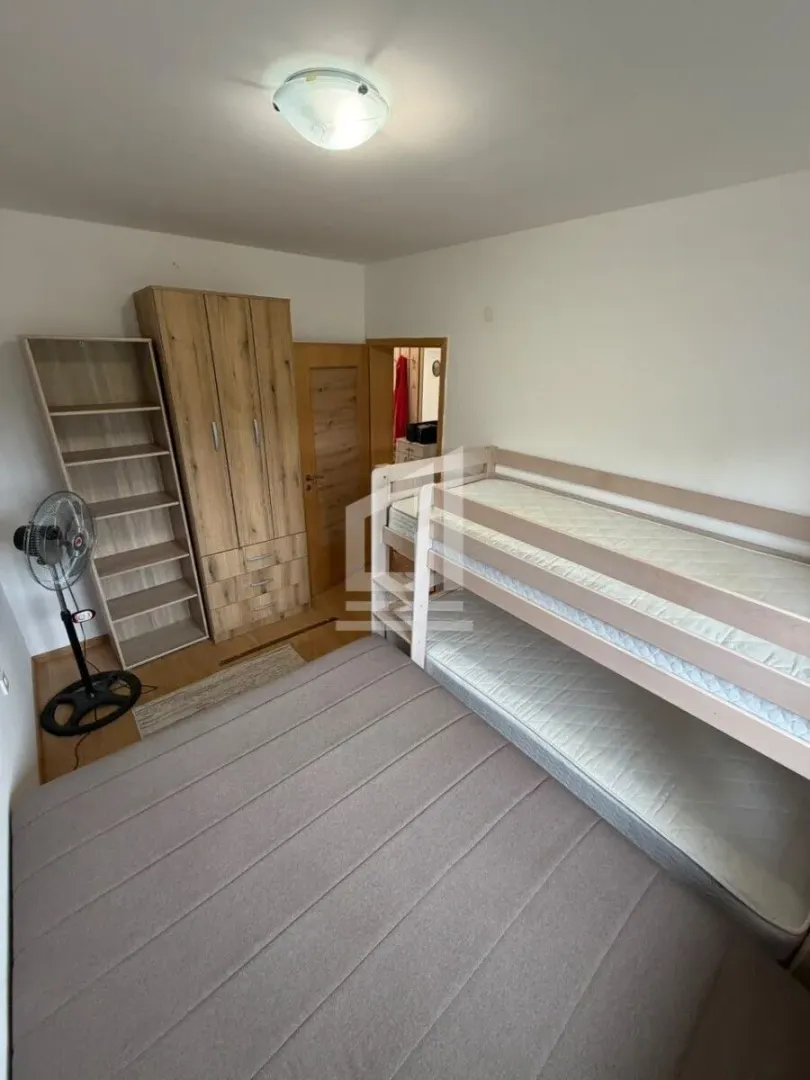 Bedroom with a bunk bed, wooden wardrobe and shelving unit.