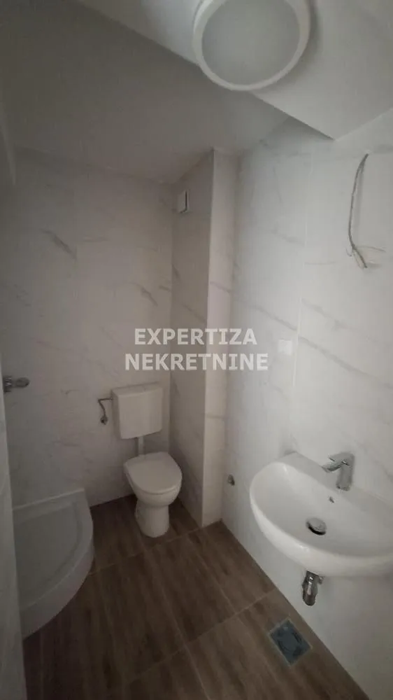 Small bathroom with a shower, washbasin, and toilet.