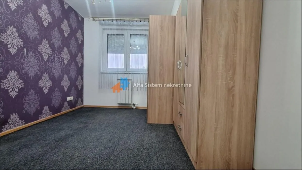 Bedroom with carpet, fitted wardrobe, and a window.