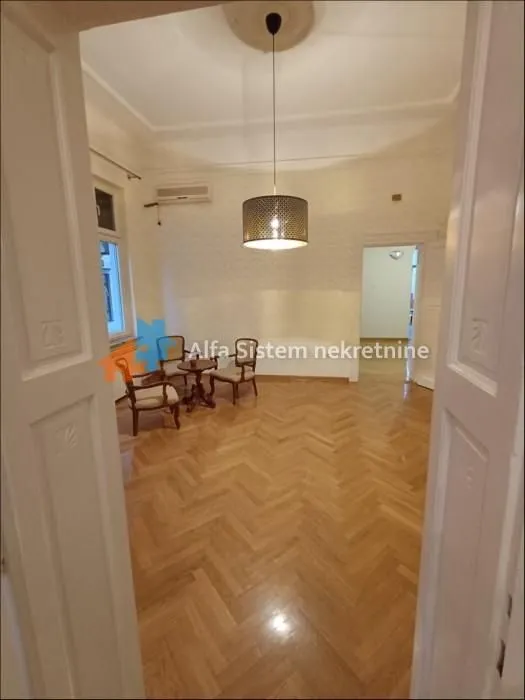 View from the doorway into the living room with parquet flooring and several chairs.