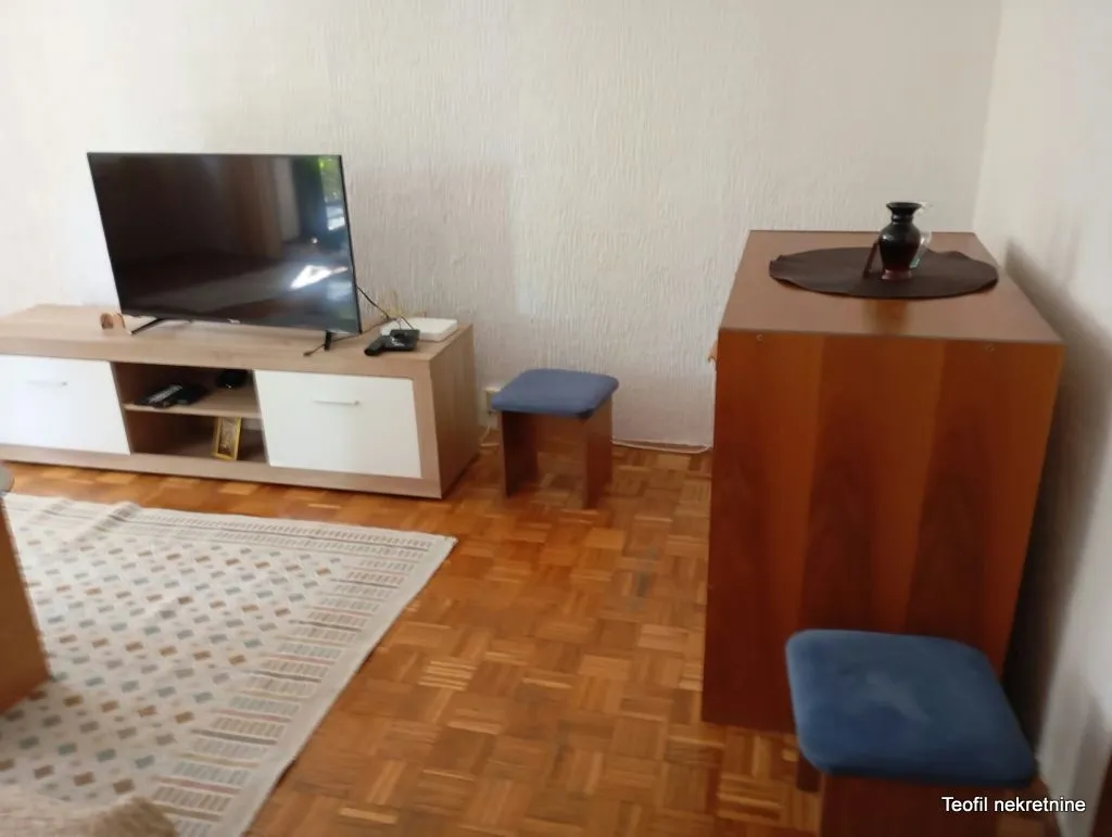 Part of the living room with a TV on a cabinet and parquet flooring.