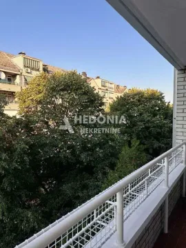 Pogled sa balkona na zeleno drveće i okolne zgrade. - image 12
