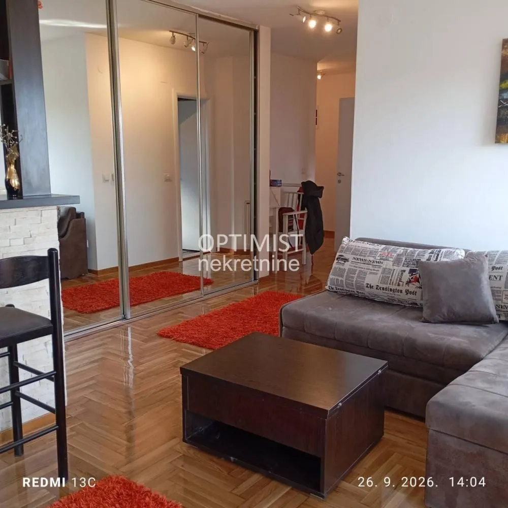 Living room with a sofa, coffee table, and built-in mirrored closet.