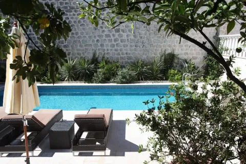 Yard with a swimming pool and sun loungers in front of a stone house. - image 12