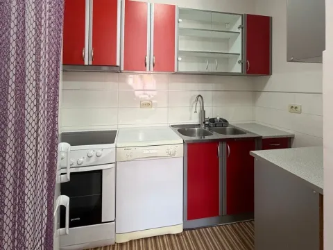 Smaller kitchen with red cabinets, stove, and sink. - image 3