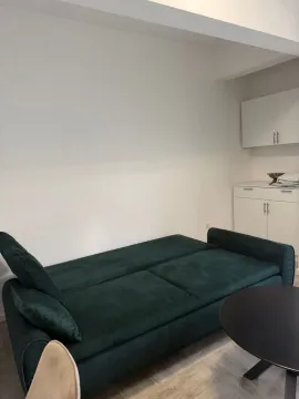 Living room with a green sofa and white furniture units. - image 3