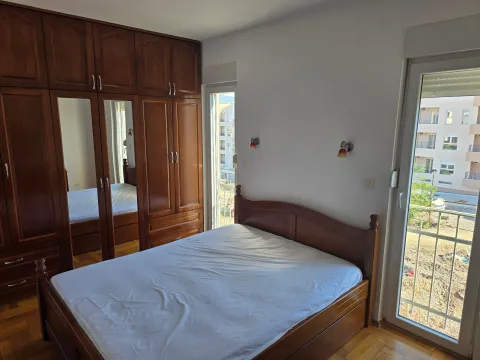 Bedroom with a large double bed, wooden wardrobe, and balcony doors. - image 7