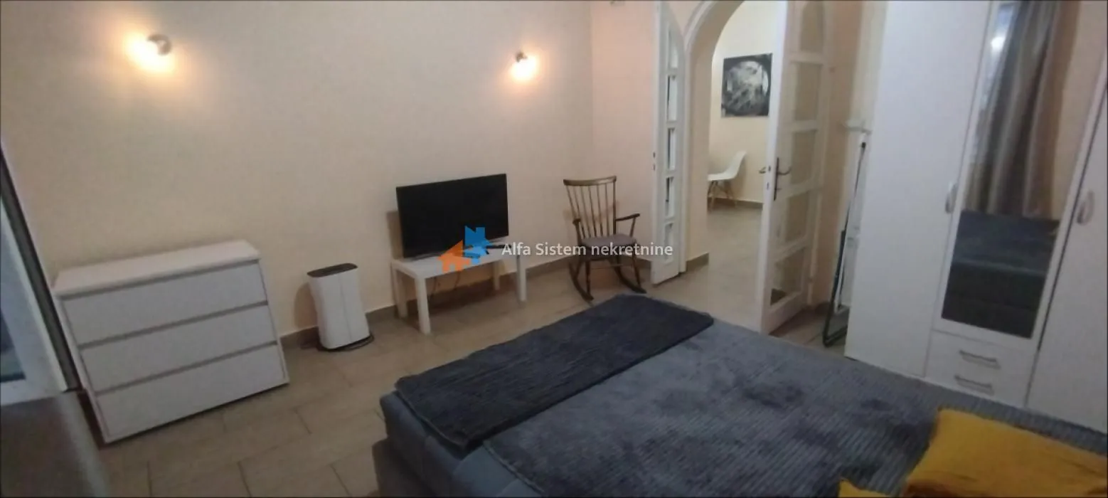 Furnished bedroom with a double bed, wardrobe, and television.
