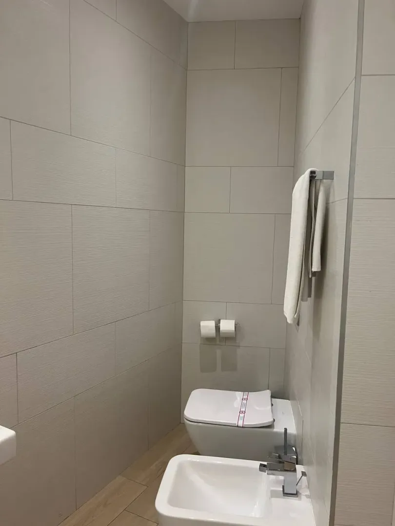 Modernly equipped bathroom with white sanitary ware and beige wall tiles.