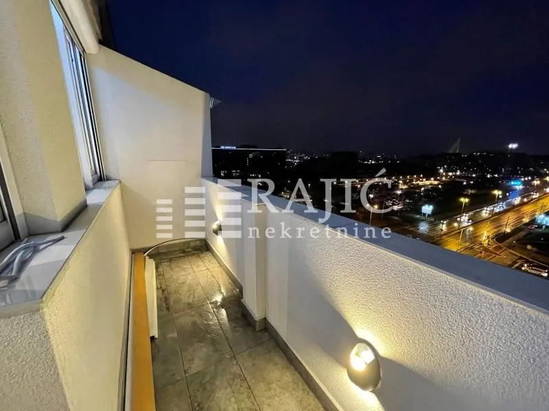 Covered balcony with a night view of the city.