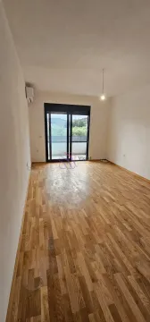 Prazna prostorija sa drvenim parketom i izlazom na terasu. - image 2