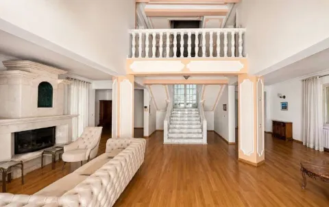 Spacious living room with a fireplace, gallery, and interior staircase. - image 8