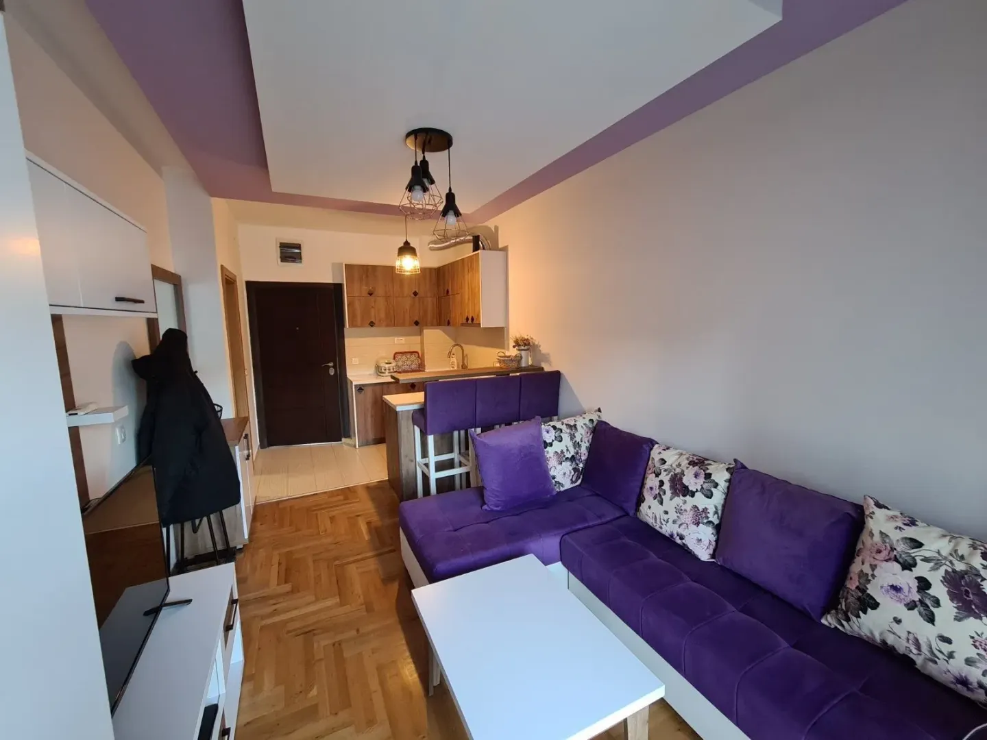 Living room with sofa set and open kitchen.