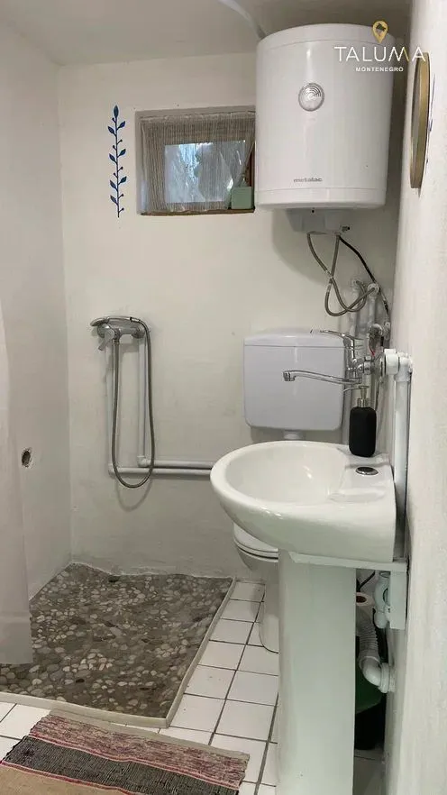 Manje kupatilo sa umivaonikom, WC šoljom, tuš prostorom i bojlerom.