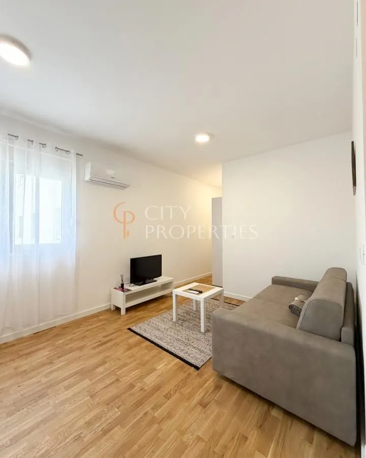 Manja dnevna soba sa garniturom, TV-om i parketom.