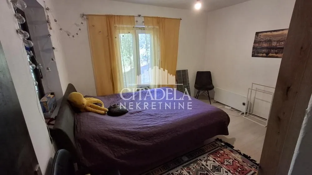 Nameštena spavaća soba sa bračnim krevetom i prozorom.