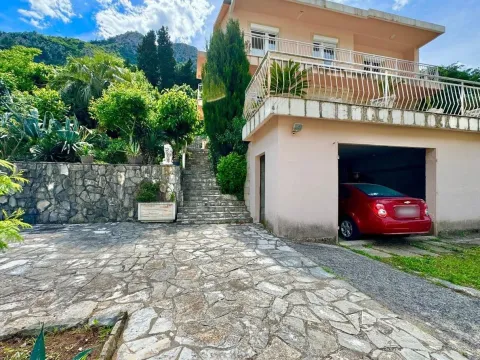 Dvorište kuće sa popločanim prilazom, garažom, terasom i stepeništem koje vodi u zelenilo. - image 6