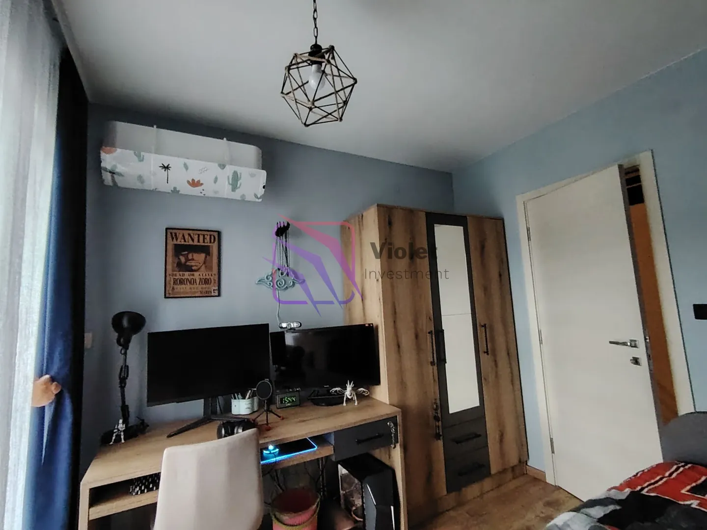 Dječja soba sa radnim stolom, računarom i drvenim ormarom.
