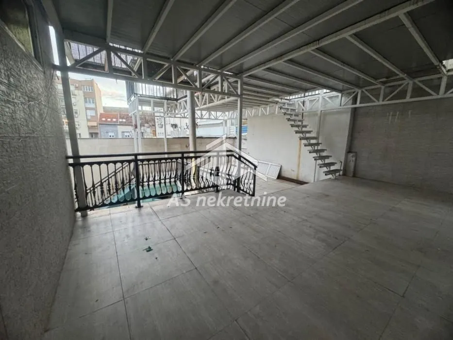 Large covered terrace with stairs and a metal railing.