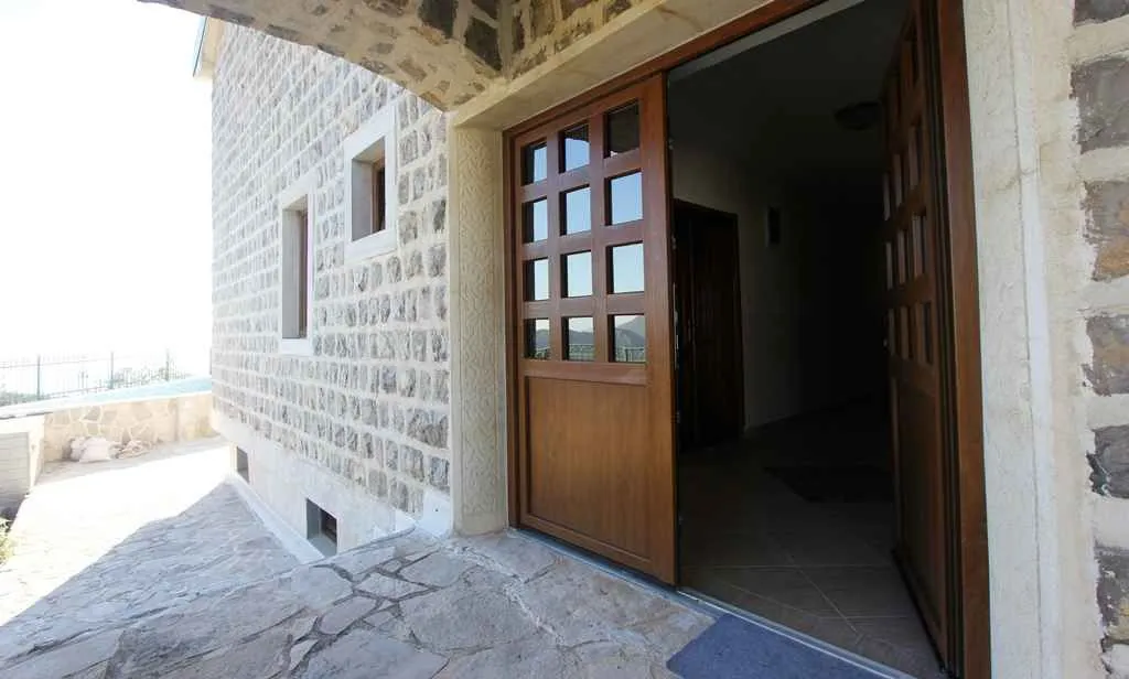 Ulaz u tradicionalnu kamenu kuću sa drvenim vratima.