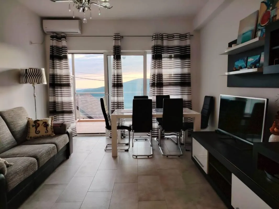 Dnevna soba sa garniturom za sjedenje, trpezarijom i izlazom na terasu.