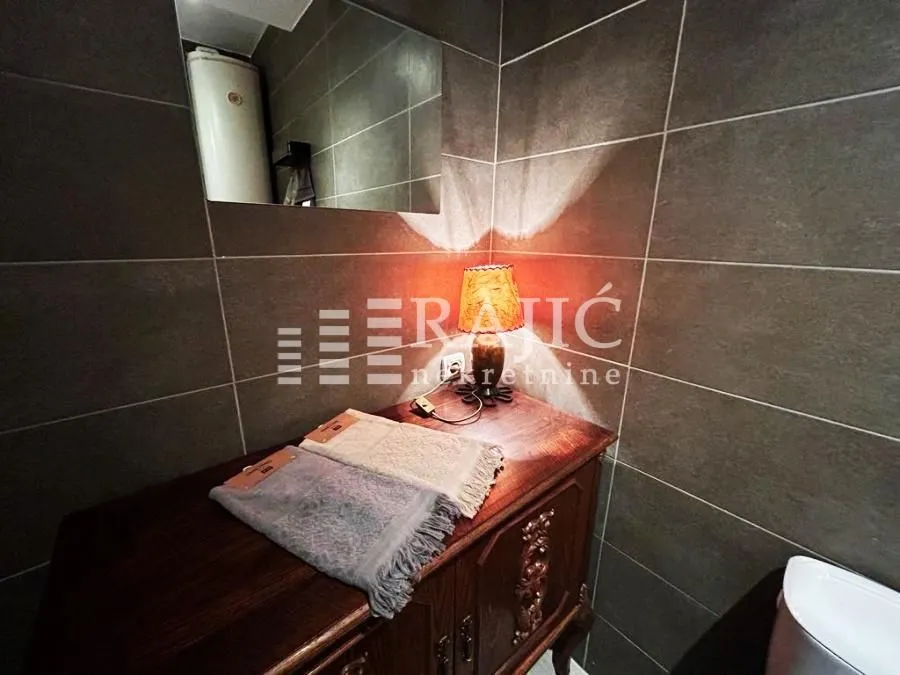 Small bathroom with tiled walls, a wooden cabinet, and a decorative lamp.