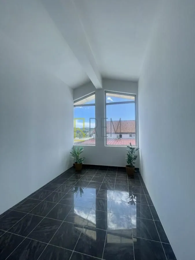 Empty bright room with dark floor tiles and large windows.