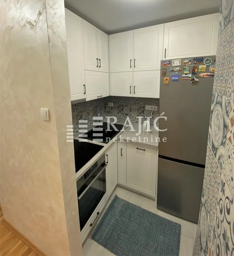 Smaller white kitchen with built-in appliances and a refrigerator.