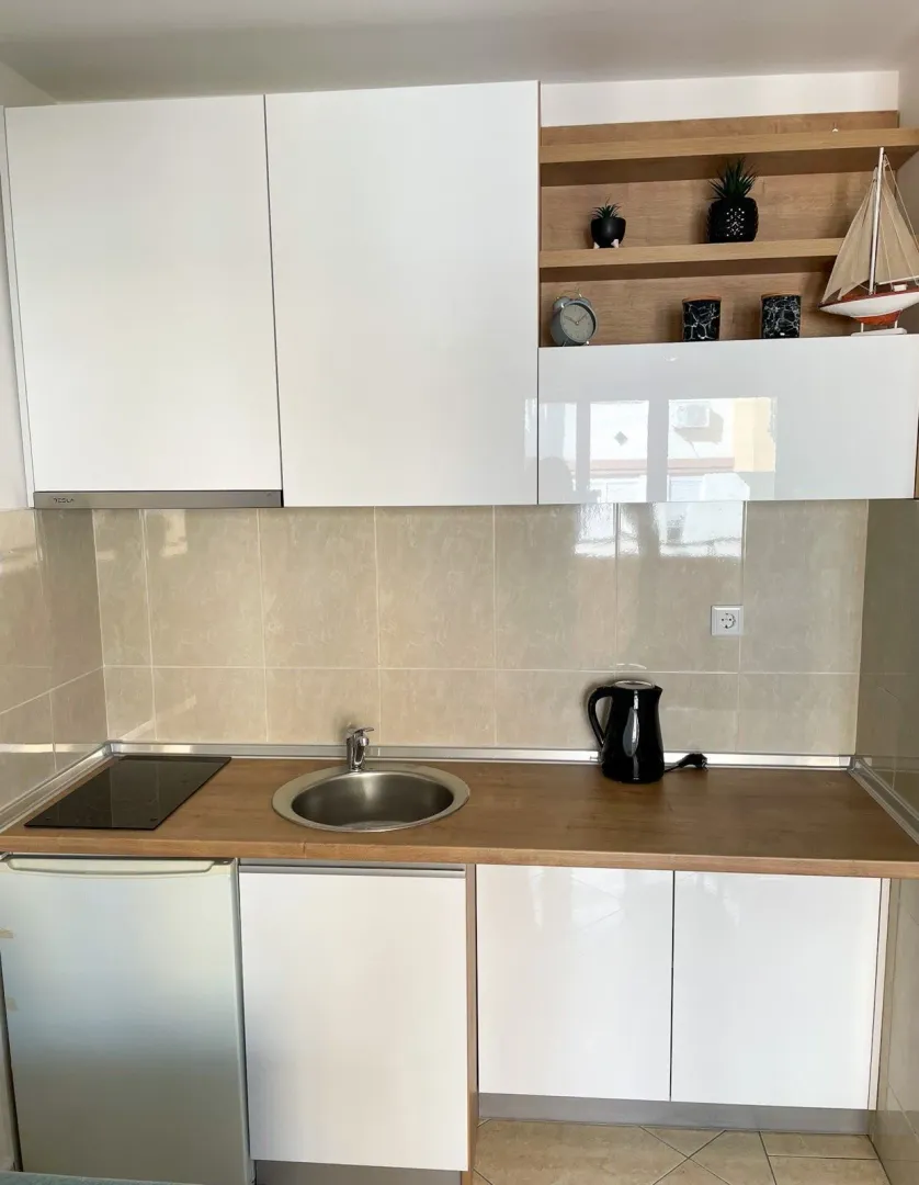 Small kitchen with white cabinets, wooden countertop, and built-in sink.