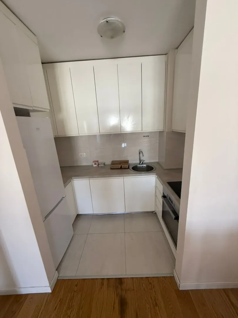 Small white kitchen with built-in appliances and a refrigerator.
