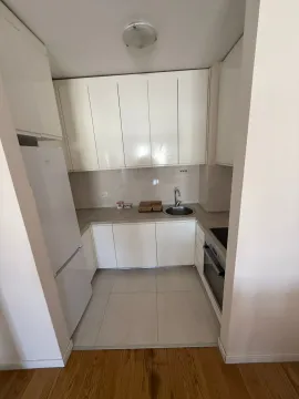 Small white kitchen with built-in appliances and a refrigerator. - image 2