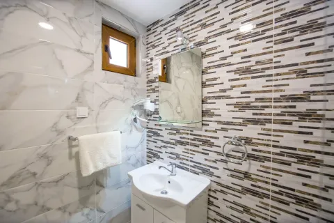 Modernly equipped bathroom with a washbasin, mirror, and tiles. - image 7