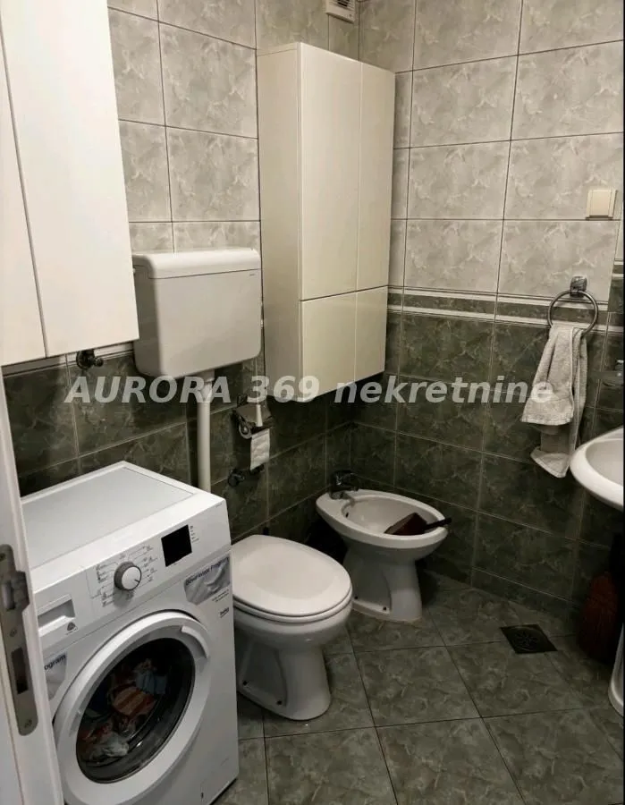 Kupatilo opremljeno sanitarijama, tuš kabinom i mašinom za veš.