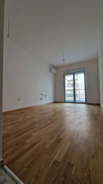 Prazna neopremljena prostorija sa drvenim podom i balkonskim vratima. - image 4