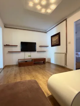 Living room with wooden flooring, TV, and media console. - image 11