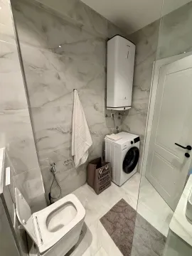 Modern bathroom equipped with a washing machine and water heater. - image 12