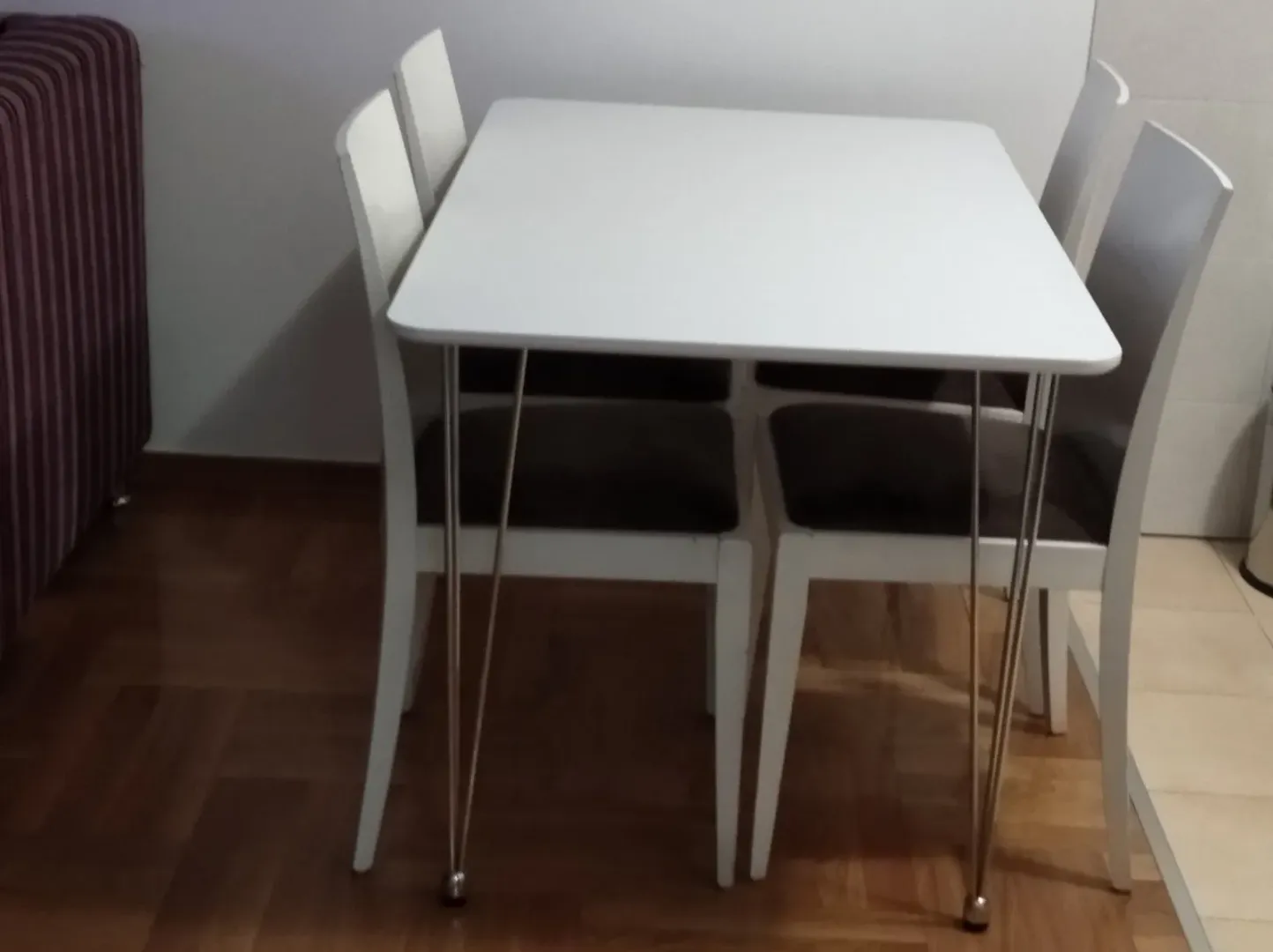 Bijeli trpezarijski sto sa četiri stolice u enterijeru.