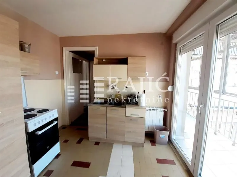 Smaller kitchen with wooden cabinets and access to the terrace.