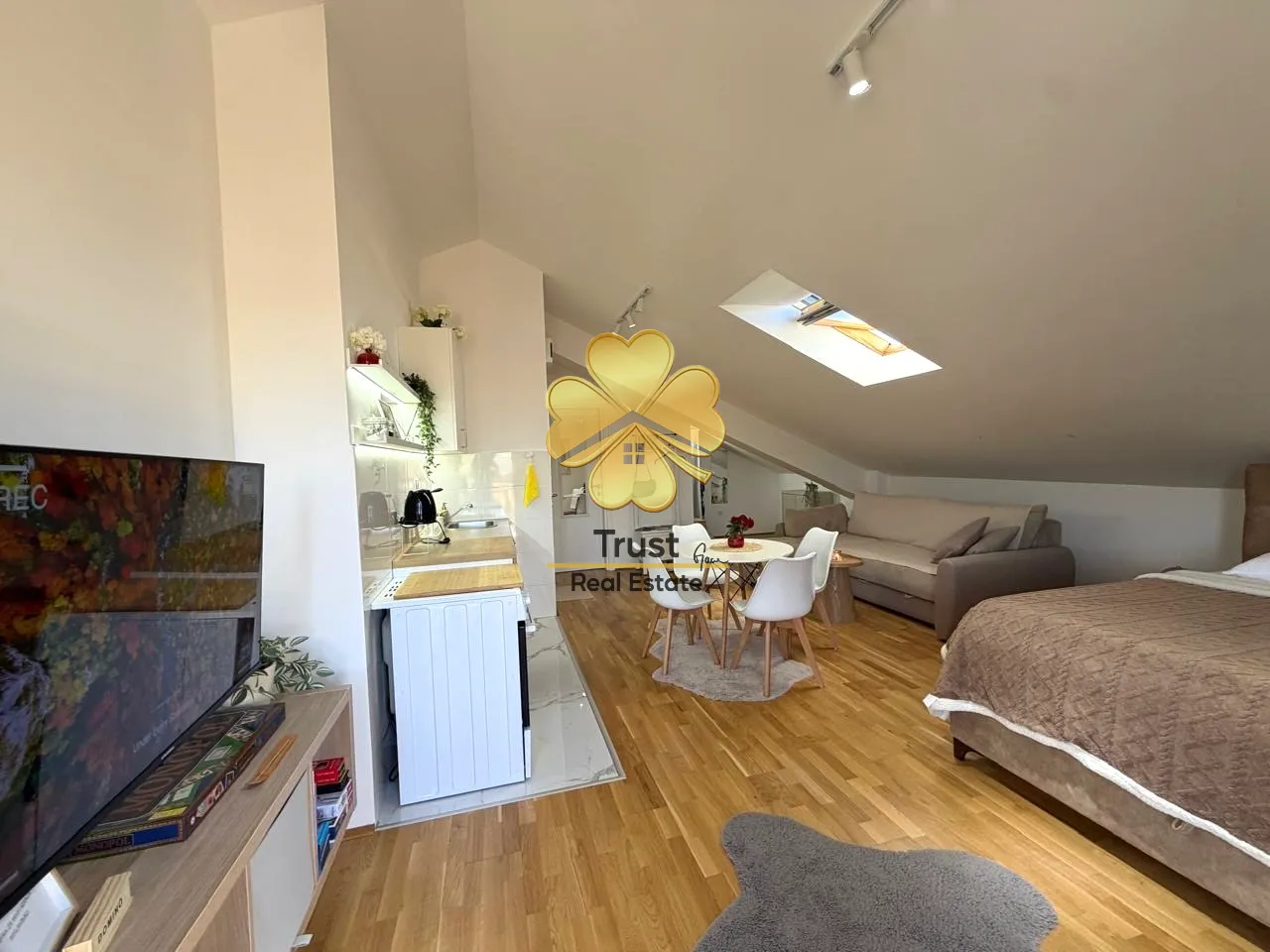 A view of the spacious attic living room with a kitchen and dining area.