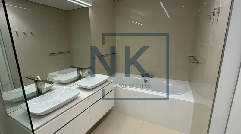 Modern bathroom with double sink and bathtub.