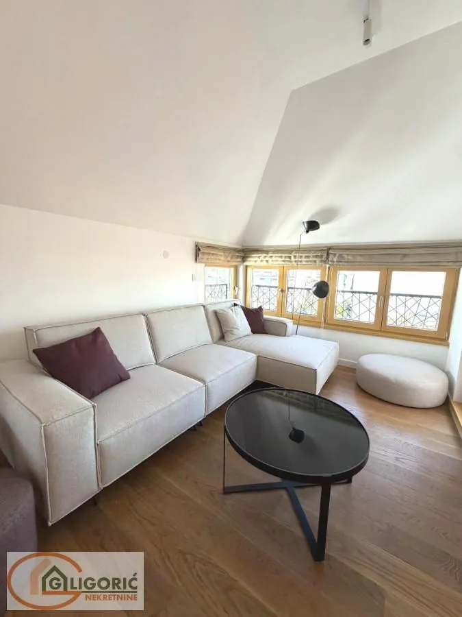Living room with a sectional sofa, coffee table, and windows.