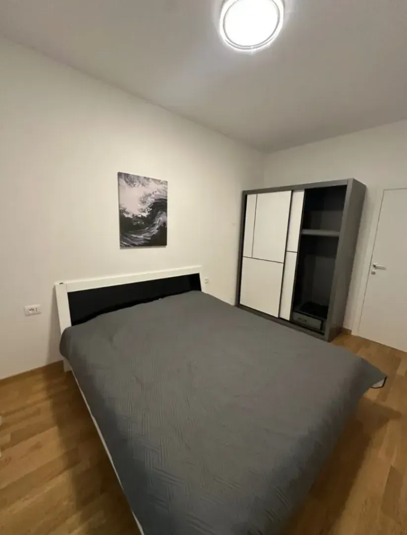 Namještena spavaća soba sa bračnim krevetom i ormarom.